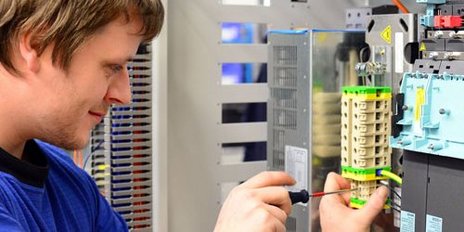Ein Elektroniker der an einer Reihenklemme schraubt