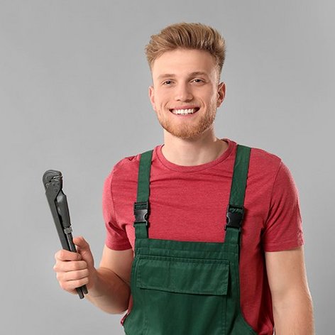 EIn junger Anlagenmechaniker mit einer Rohrzange in der Hand